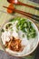 Oriental clear chicken soup with noodles, fried onions, green onions and cilantro close-up in a bowl on the table. Vertical top