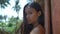 Oriental girl with long dark hair posing against exotic Palm trees on backdrop