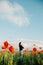 Oriental girl is standing in a field of poppies.young girl enjoys a summer sunset. Copy space