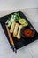 Oriental, Plate with spring rolls chop sticks, three spring rolls, spring onions, lime, lemon, sweet chilli sauce.