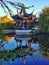 An oriental style pergola reflecting in the waters of the pond at Lan Yuan chinese garden in Dunedin New Zealand