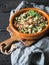 Oriental tabbouleh salad with couscous, vegetables and herbs in a brown bowl on a dark wood background