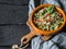 Oriental tabbouleh salad with couscous, vegetables and herbs in a brown bowl on a dark wood background