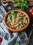 Oriental tabbouleh salad with couscous, vegetables and herbs in a brown bowl on a dark wood background