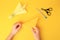 Origami art. Child holding paper figure on yellow background, closeup and top view