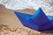 Origami blue paper boat on sandy beach for concept design, beautiful blue paper ship, close up