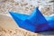 Origami blue paper boat on sandy beach for concept design, beautiful blue paper ship, close up