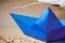 Origami blue paper boat on sandy beach for concept design, beautiful blue paper ship, close up