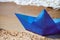 Origami blue paper boat on sandy beach for concept design, beautiful paper ship on shore, close up