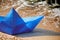 Origami blue paper boat on sandy beach for concept design, beautiful paper ship on shore, close up