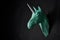 Origami green unicorn`s head hanging on black wall.