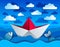 Origami paper ship toy swimming in curvy waves of the sea and clouds in the sky.