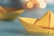 Origami yellow sailing boat on a sea made with blue paper