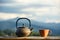 An original cast-iron kettle and a cup overlooking the mountain landscape.