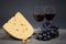 Original composition of gastronomic products. Cheese with a bunch of grapes and two glasses of red wine