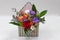 Original floral arrangement gift of fresh flowers in a box in the form of an envelope on a light background.