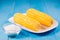 Ð¡orn with salt. Selective focus. Yellow corn in a white bowl and salt glass on blue wooden background