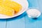 Ð¡orn with salt. Selective focus. Yellow corn in a white bowl and salt glass on blue wooden background