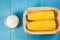 Ð¡orn with salt. Top view. Yellow corn in small basket and salt glass on blue wooden background