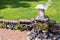 Ornamental low height brick wall and exterior light; green meadow in the background