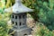 Ornamental stone lantern with among fresh green plants japanese design, outdoor garden stone statue decoration