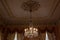 Ornate crystal chandelier in a beautiful room with extravagant curtains and plaster mouldings, soft colors