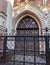 Ornate doors behind black forged gates of gothic mansion