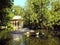 An ornate gazebo beside an ornamental duck pond.