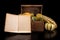 Ornate pumpkin in a old wooden crate and a book. Vegetables and old publications on the dark table