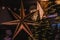 Ornate star decoration hanging from the ceiling against a backdrop of a festive Christmas tree