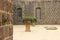 Ornate wide pot in a stone courtyard with overflowing green vegetation at a heritage home with ornate carved details