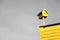 Ornate yellow birdhouse atop a building, with a cloudy gray sky in the background