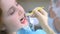 Orthodontist covering special gel on woman teeth in dentistry using brush.