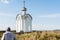 Orthodox chapel white with a transparent facade on the background of the panorama of the sea and blue sky in a field