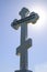 Orthodox cross against the blue sky and the sun. Cross in the backlight of the sun. Symbol of the Christian faith. The inscription