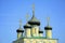Orthodox golden crosses on five domes against a blue sky with clouds