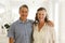 ortrait of happy senior caucasian couple in living room, embracing and smiling