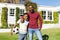 ortrait of smiling african american father with son embracing and holding football in sunny garden