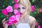 Ortrait of young woman near blooming pink rose bush