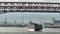 Osaka, Japan - July 10, 2022: Fully loaded cargo ship sails under bridge with light traffic