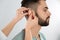 Otolaryngologist putting hearing aid in man`s ear