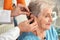 Otolaryngologist putting hearing aid in senior patient`s ear