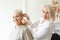Otolaryngologist putting hearing aid in senior woman\'s ear indoors