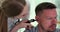 Otorhinolaryngologist examines patient ear with an otoscope closeup