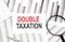 OUBLE TAXATION text on paper with calculator,magnifier ,pen on the graph background