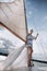 ?oung girl stands on a yacht with white sails in a flying dress