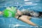 Oung man swimmer with green cap swims front crawl or forward crawl stroke in a swimming pool for competition or race