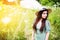 Ðoung woman in a hat stands in a meadow