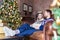 Ð¡ouple wearing warm socks and jerseys while sitting on the sofa near Christmas tree