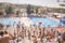 Out of focus, defocused shot, group of unrecognizable people outdoors, large crowd, swimming pool,